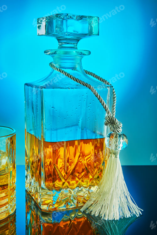 Preview: Square crystal decanter with scotch whiskey or brandy on a blue gradient background with reflection