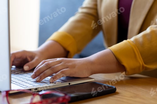 Preview: Midsection of plus size caucasian casual businesswoman using laptop at desk