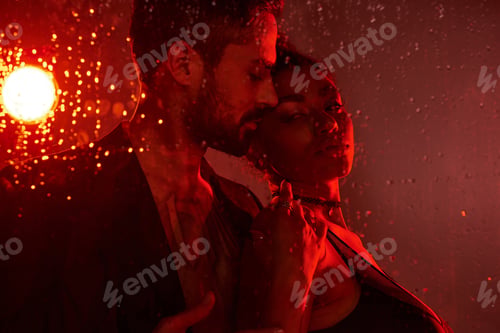 Preview: A couple shares a tender moment surrounded by raindrops, illuminated by warm red light
