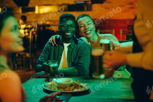 Preview: Happy African American couple drinking beer during a night out in a bar.
