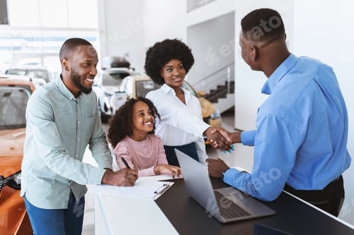 Preview: Its a deal. Black family buying new car, shaking hands with salesman, signing auto purchase