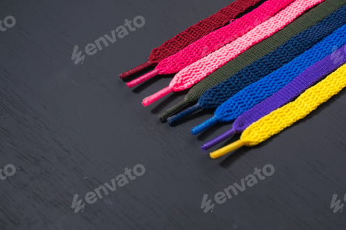 Preview: background of colored shoelaces on black wood, arranged diagonally, concept of perfection