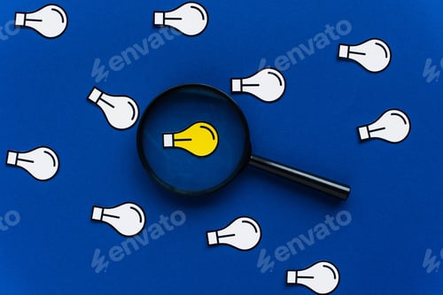 Preview: top view of paper light bulbs and magnifying glass on blue background, business concept