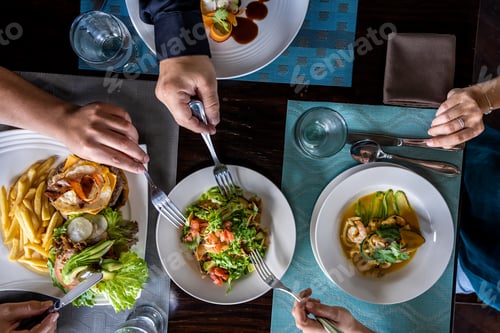 Preview: Aerial photo of people sharing the food of a raw of dishes