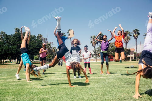 Preview: Schoolgirl soccer team doing cartwheel celebration on school sports field