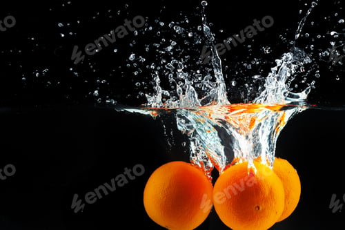 Preview: Oranges falling into water against black background, studio shot