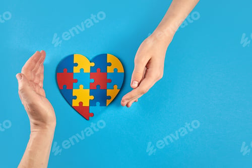 Preview: Father and autistic son hands holding jigsaw puzzle heart shape. World Autism Awareness Day