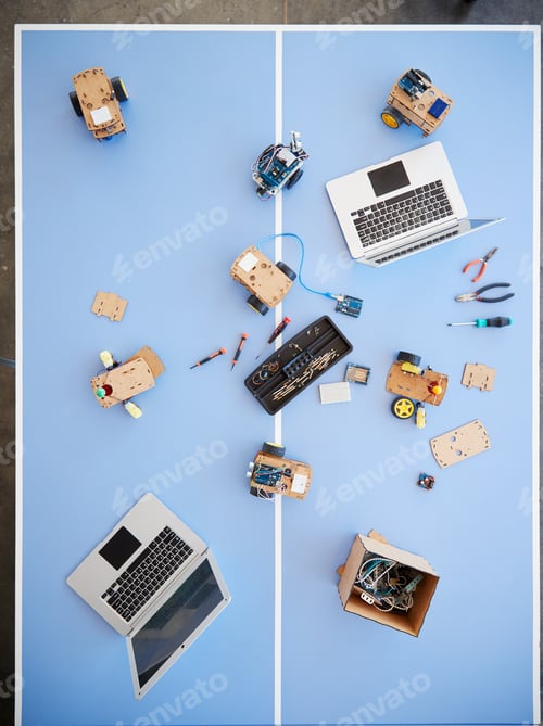 Preview: Overhead View Of Laptops And Robotic Vehicles On Table In School Computer Coding Class