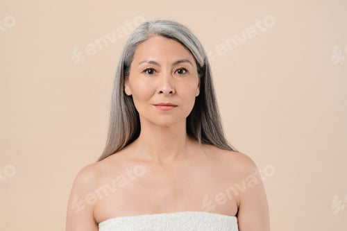 Preview: Woman in spa towel with pure aging skin isolated on beige background. Beauty rejuvenation product