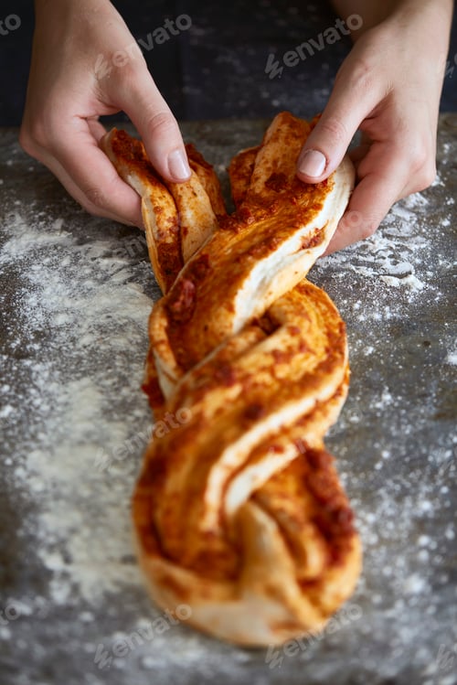 Preview: Woman's hands plaiting bread dough on floured baking tray