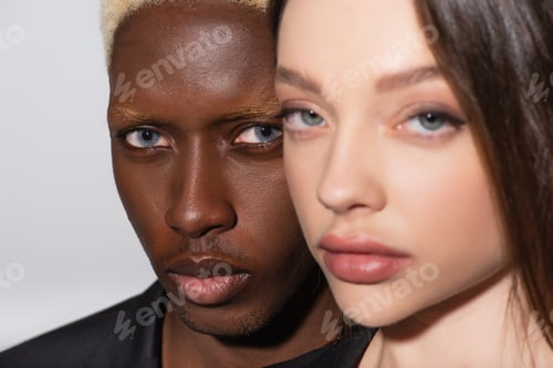 Preview: close up view of young interracial couple looking at camera isolated on grey