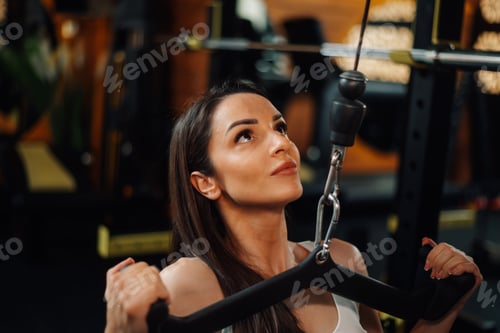 Preview: Determined sportswoman performing lat pulldown exercise in gym