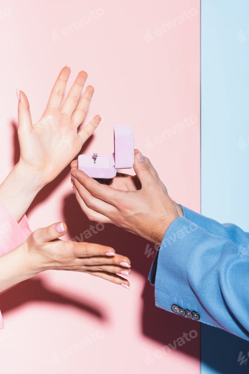 Preview: cropped view of man doing marriage proposal to woman on pink and blue background