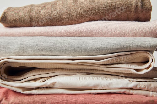 Preview: Close up view of stack of folded ironed clothes on grey