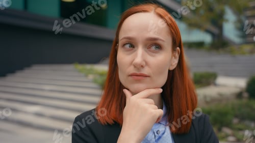 Preview: Portrait pensive thinking serious Caucasian ginger hair business woman in city outdoors