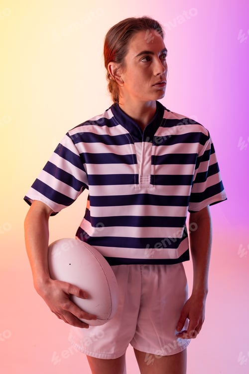 Preview: Caucasian female rugby player with rugby ball over neon pink lighting