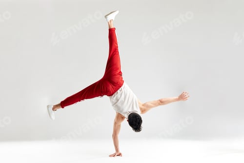 Preview: Young man in red sweatpants doing a handstand on hands on white background