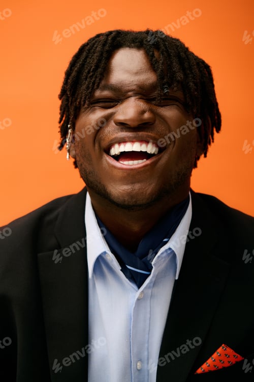 Preview: Handsome young man in stylish attire joyfully smiling against an orange backdrop