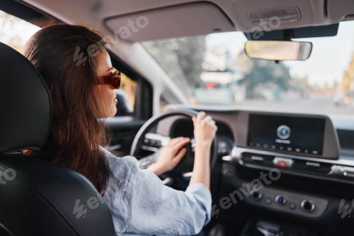 Preview: Woman driving car, focused on dashboard screen, hands on steering wheel, interior view