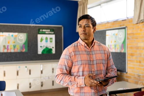 Visualização: Retrato de professor masculino birracial feliz com tablet na sala de aula do ensino fundamental