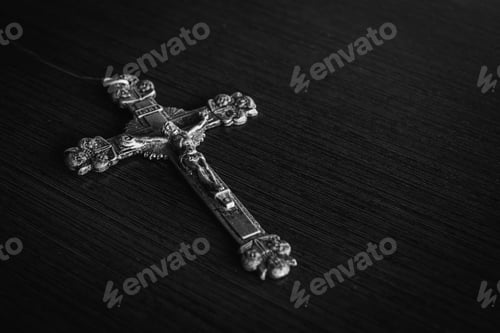 Preview: Closeup shot of a metal cross on a wooden black table