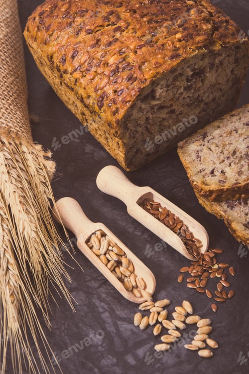 Preview: Wholegrain bread for breakfast, ingredients for baking and ears of rye or wheat grain. Vintage photo
