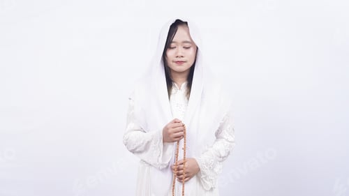 Preview: Asian muslim woman wearing prayer beads pray with tasbih in white background
