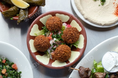 Preview: Top view of falafel with ingredients in a plate and some other dishes on the side
