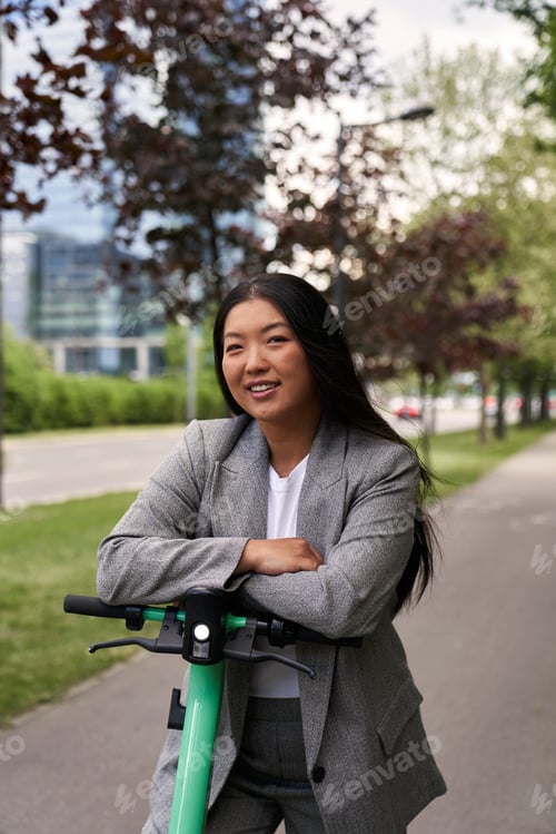 Preview: Portrait of Chinese woman riding on electric scooter in business outfit