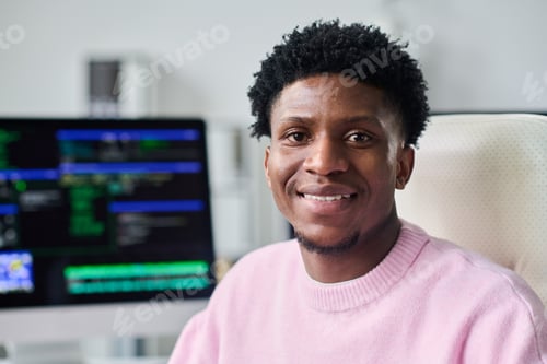 Preview: Portrait of Young Black Man Smiling While Working at Computer Desk