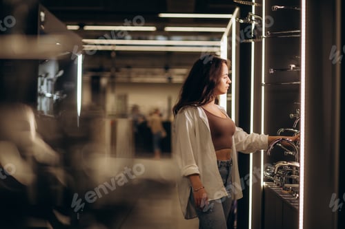 Preview: Woman at the building market choosing faucet