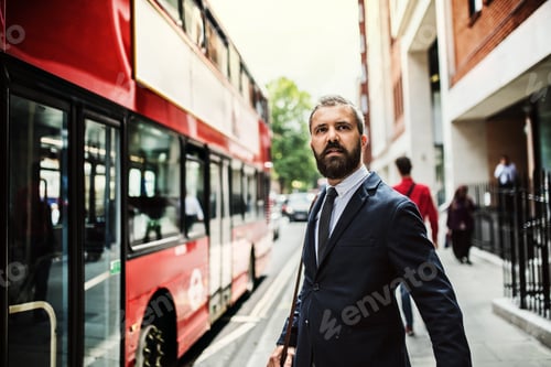Preview: Hipster businessman standing on the street, waiting for the bus in London.