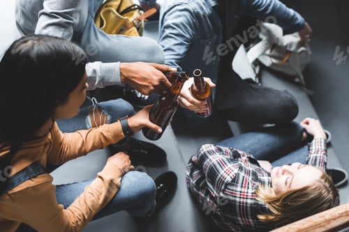 Preview: partial view of teenagers sitting on stairs, smiling and clinking
