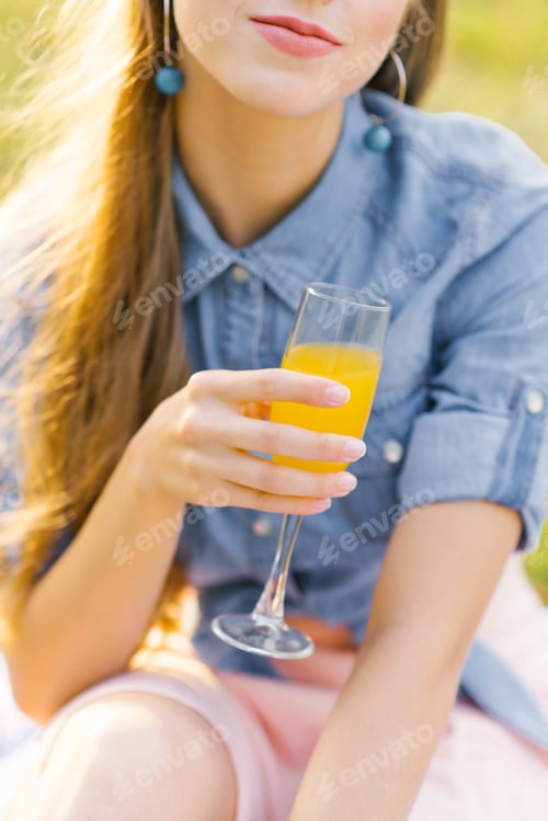 Preview: Glass of orange juice in the hand of a young woman