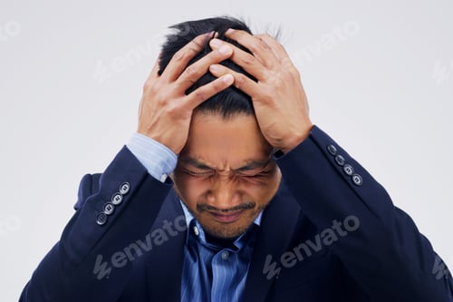 Preview: Shot of a young man holding his head while suffering from a headache against a grey background