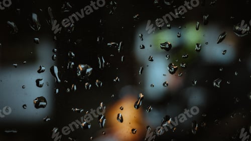 Preview: Rain droplets running down a window glass in a dark setting.