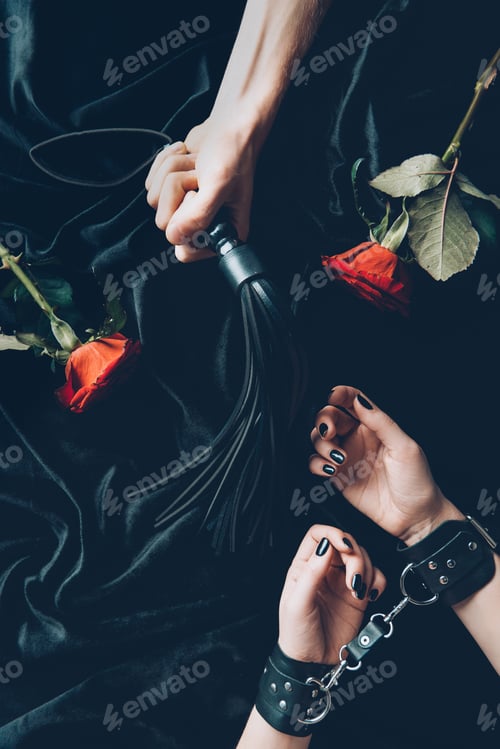 Preview: cropped shot of woman in black handcuffs and man holding leather whip