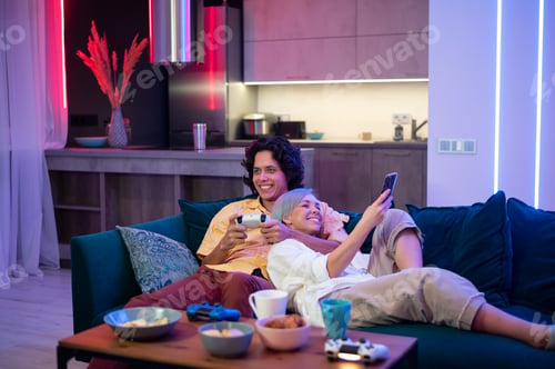 Preview: Young woman spending time with her boyfriend at home. She using smart phone while he is playing