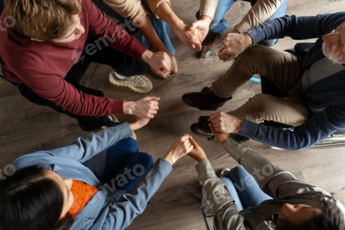 Preview: Diverse group of people holding hands in circle during support meeting
