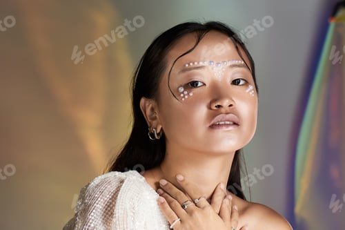 Preview: Creative makeup artistry on an asian young woman with pearls in a vibrant studio setting