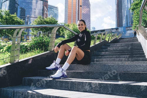 Preview: Glad sportswoman sitting on steps in city park