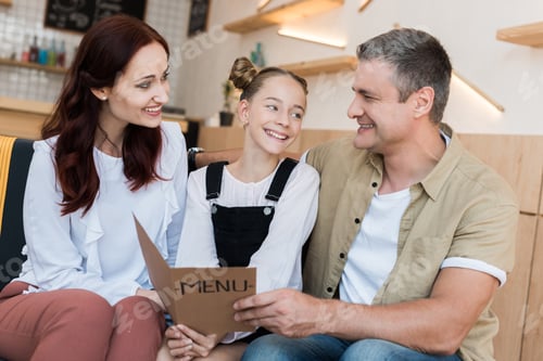 Preview: beautiful happy family looking at menu list in cafe