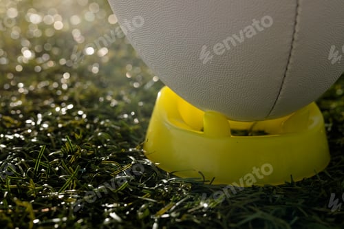 Preview: White rugby ball in yellow stand over grass with copy space, in slow motion