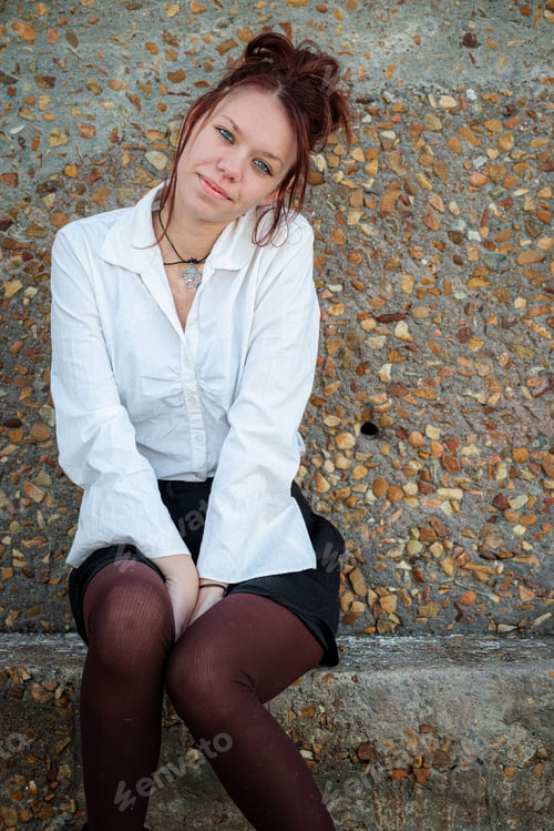 Preview: Red-haired girl in a formal outfit in front of a stone wall