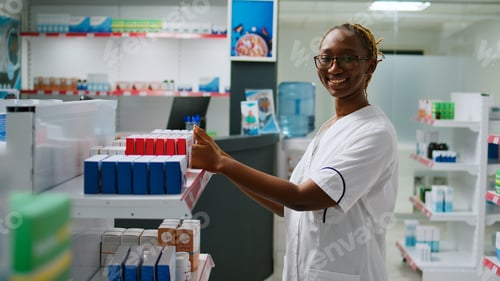 Preview: Smiling female pharmacist analyzing boxes of medicine on pharmacy shelves