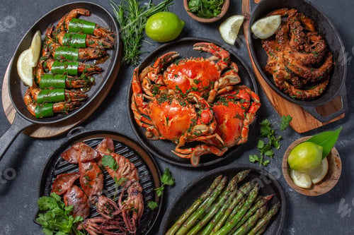 Preview: Set table with seafood dishes - cooked crabs, tiger shrimps, grilled octopus and squids on cast iron