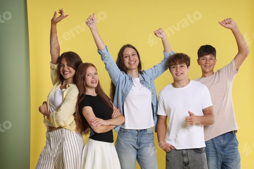 Preview: Portrait of happy teenage friends on yellow background