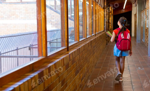 Preview: Caucasian schoolgirl walking with school bag and books at school corridor, copy space