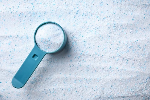Preview: Measuring spoon with laundry powder, top view. Space for text