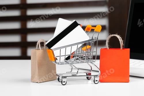 Preview: Online shopping concept. Shopping cart, laptop on the desk